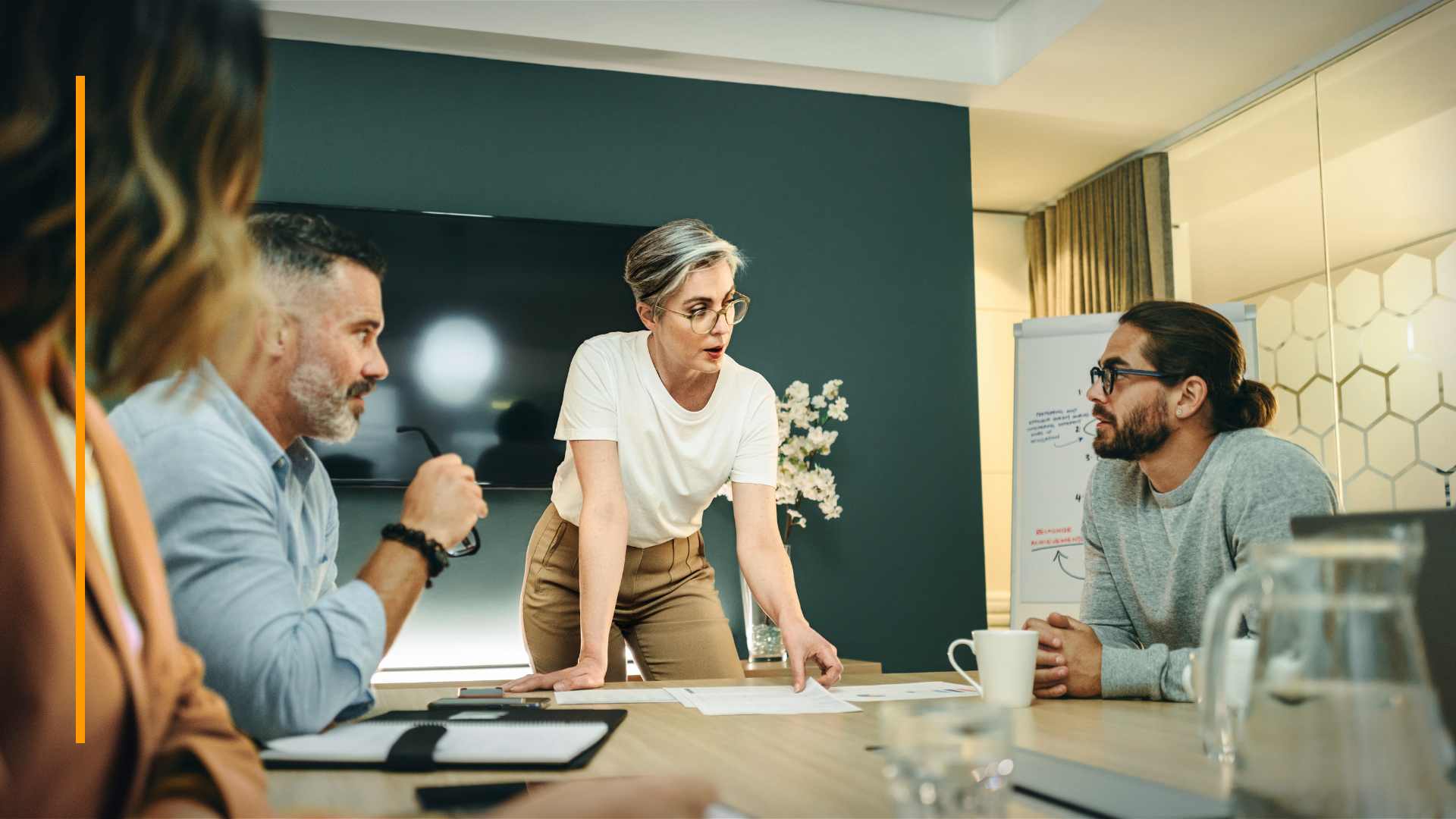 Scène de réunion d’affaires avec une barre d’accent orange verticale à gauche, utilisée comme traitement visuel promotionnel pour les webinaires de la marque.